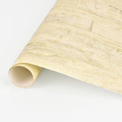 Lindens Wood Wallpaper by York Wallcoverings, a rolled sheet of textured light beige wallpaper with a subtle stone or brick pattern, displayed on a white background.
