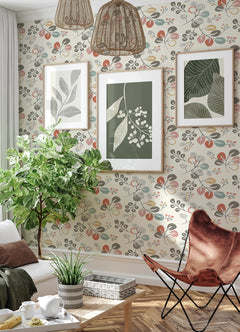 Sunlit living room featuring York Wallcoverings’ Jonah Leaf Trail Wallpaper, with botanical art prints on the wall, a large leafy potted plant, wicker pendant lights, modern furniture, and sheer white curtains at the window.