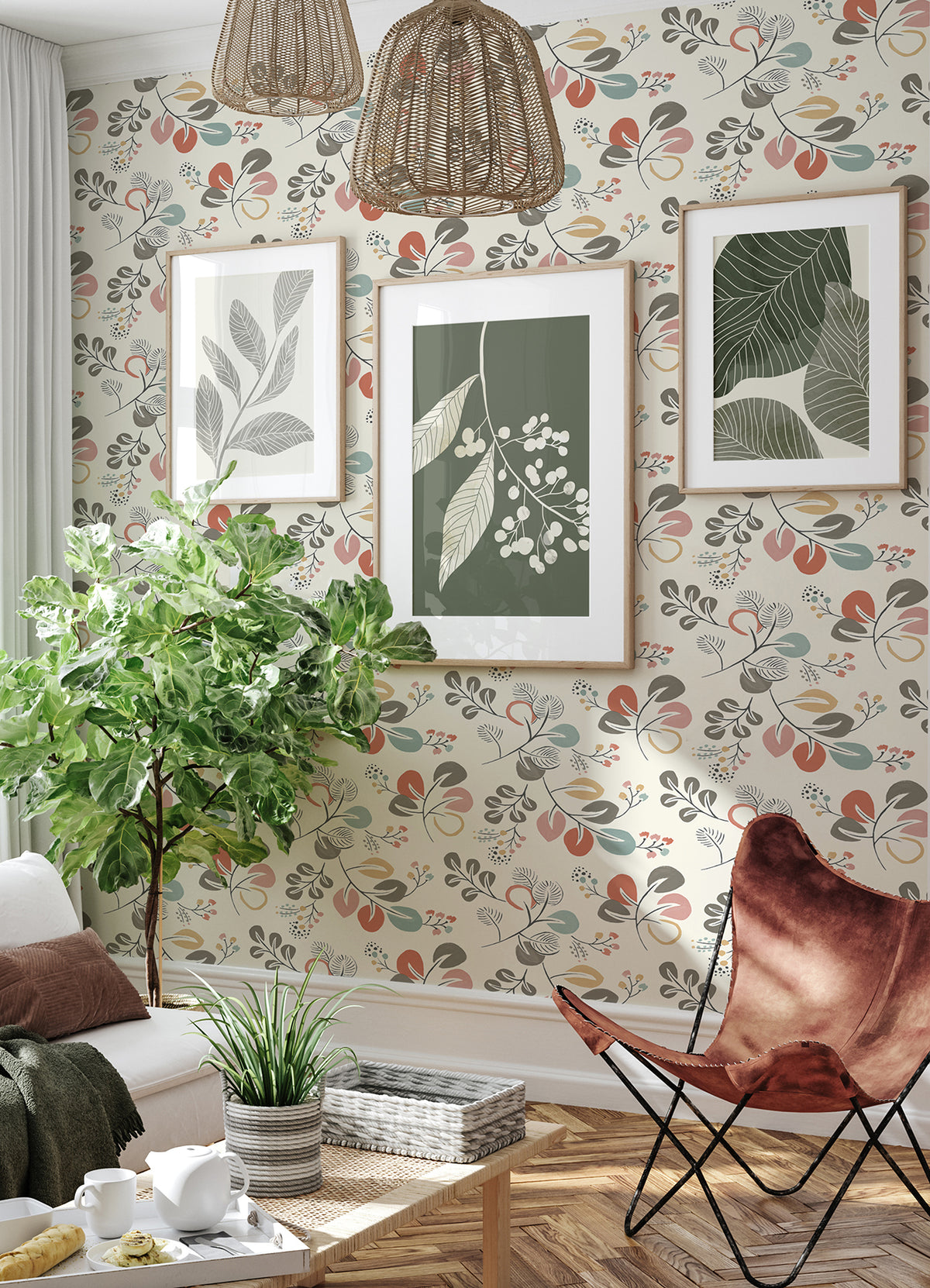A cozy living room featuring Jonah Leaf Trail Wallpaper by York Wallcoverings, three botanical prints on the wall, a large leafy plant, wicker light fixtures, and a brown butterfly chair beside a small white coffee table topped with a plant.