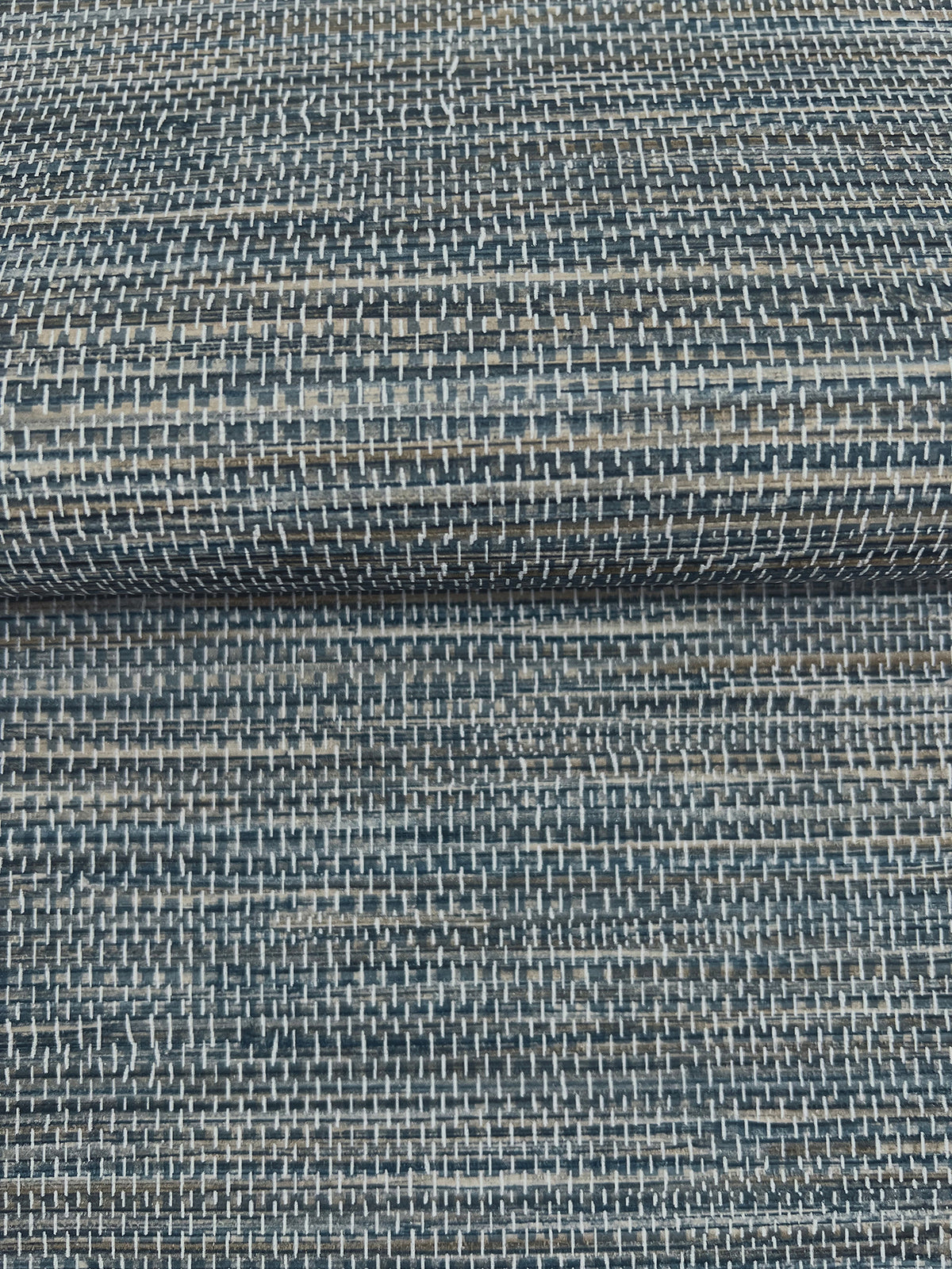 A close-up of dark blue and grey Winn Faux Grasscloth Wallpaper by York Wallcoverings, featuring a woven, horizontal texture.