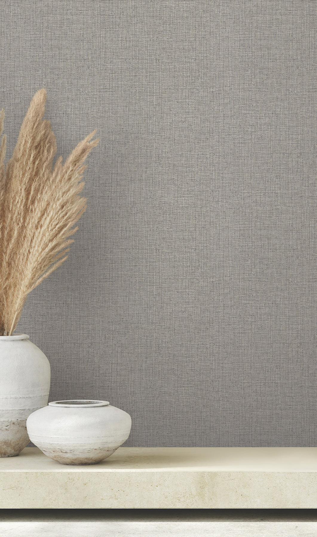 Clarkson Woven Wallpaper in gray with a subtle woven texture, shown behind two decorative vases on a ledge.