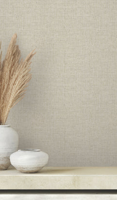 Two ceramic vases, one holding tall dried grasses, sit on a shelf in front of light beige, textured Clarkson Woven Wallpaper.