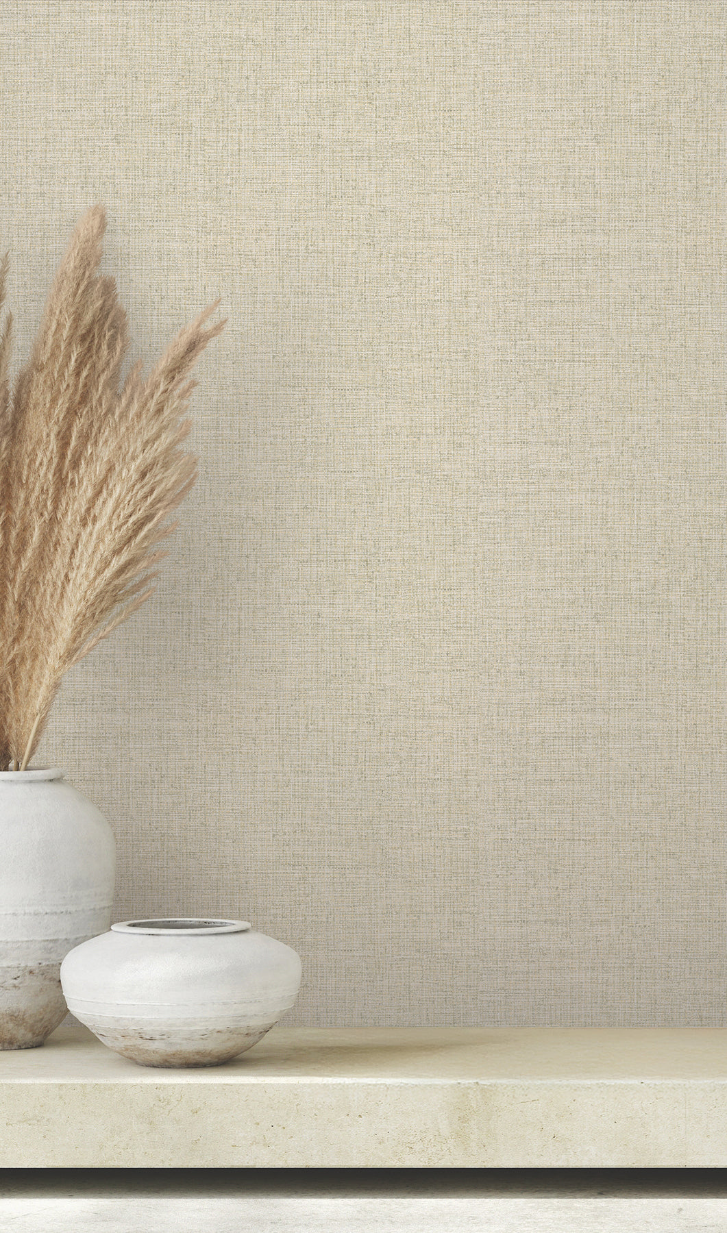 Clarkson Woven Wallpaper in beige with a fine texture sits behind two ceramic vases filled with dried ornamental grass.