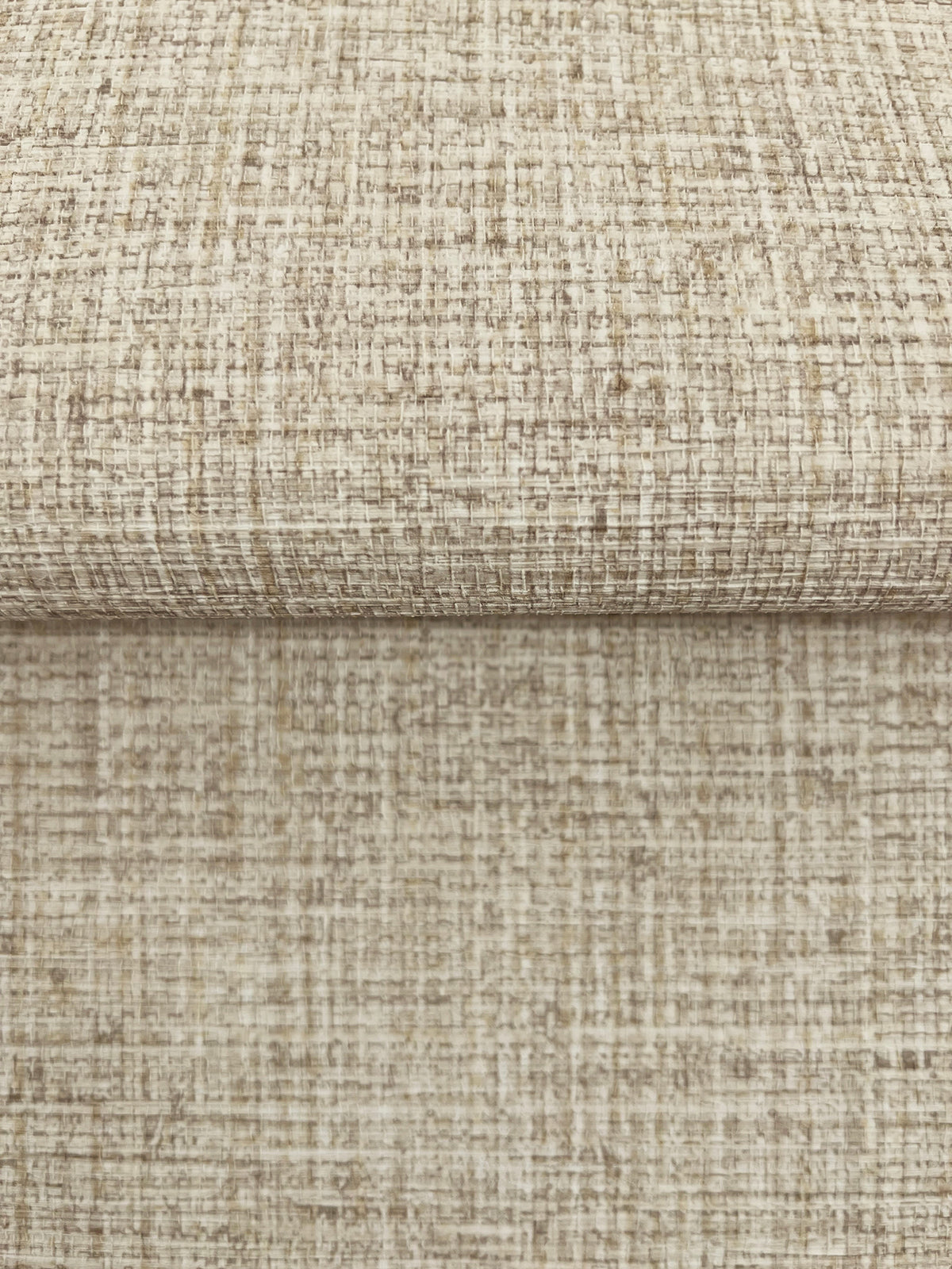 A close-up of Clarkson Woven Wallpaper, showing folded sheets with a textured, neutral-toned woven fabric pattern.