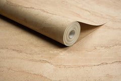 A roll of York Wallcoverings Chesapeake Morgana Stone Wallpaper lies partially unrolled on a matching surface, displaying its beige, stone-like textured pattern.