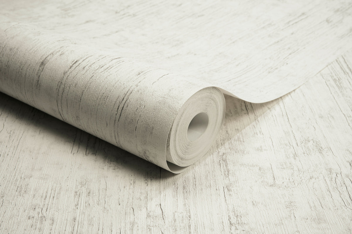 A partially unrolled roll of Chesapeake Ramona Distressed Texture Wallpaper by York Wallcoverings, featuring a light-colored, textured design with subtle gray lines and patterns on a matching surface.