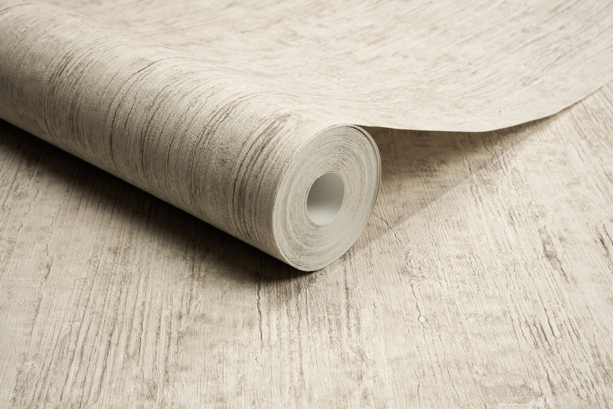 A close-up of a roll of Chesapeake Ramona Distressed Texture Wallpaper by York Wallcoverings, partially unrolled on a matching textured surface.