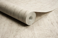 A close-up of a roll of Chesapeake Ramona Distressed Texture Wallpaper by York Wallcoverings, partially unrolled on a matching textured surface.