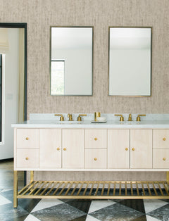 Modern bathroom with two rectangular mirrors above a double-sink vanity. The vanity features light wood cabinets, gold faucets, and an open slatted shelf. Black and white geometric floor tiles complement the neutral Chesapeake Ramona Distressed Texture Wallpaper by York Wallcoverings on the walls.