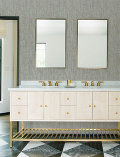 Modern bathroom featuring the Chesapeake Ramona Distressed Texture Wallpaper by York Wallcoverings, complemented by a double sink vanity, gold fixtures, two rectangular mirrors, light wood cabinetry, and a geometric black-and-white tile floor.