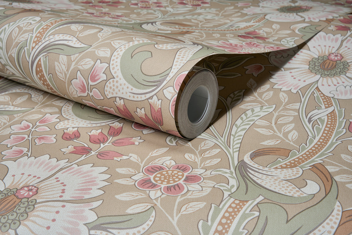 A close-up of the Chesapeake Liora Floral Trail Wallpaper by York Wallcoverings, featuring a floral and leaf pattern in shades of beige, pink, green, and white. The wallpaper is partially unrolled on a matching patterned surface.