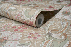 A close-up of the Chesapeake Liora Floral Trail Wallpaper by York Wallcoverings, featuring a floral and leaf pattern in shades of beige, pink, green, and white. The wallpaper is partially unrolled on a matching patterned surface.