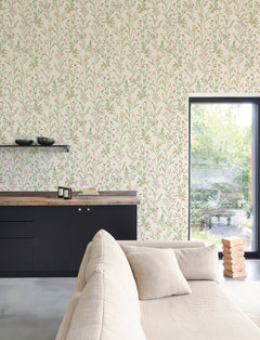 A modern living room with a beige sofa, black cabinets, wooden countertop, and a window overlooking a green garden features York Wallcoverings’ Chesapeake Laverne Wildflowers Wallpaper. Two black bowls and a stack of wooden blocks are also visible in the scene.