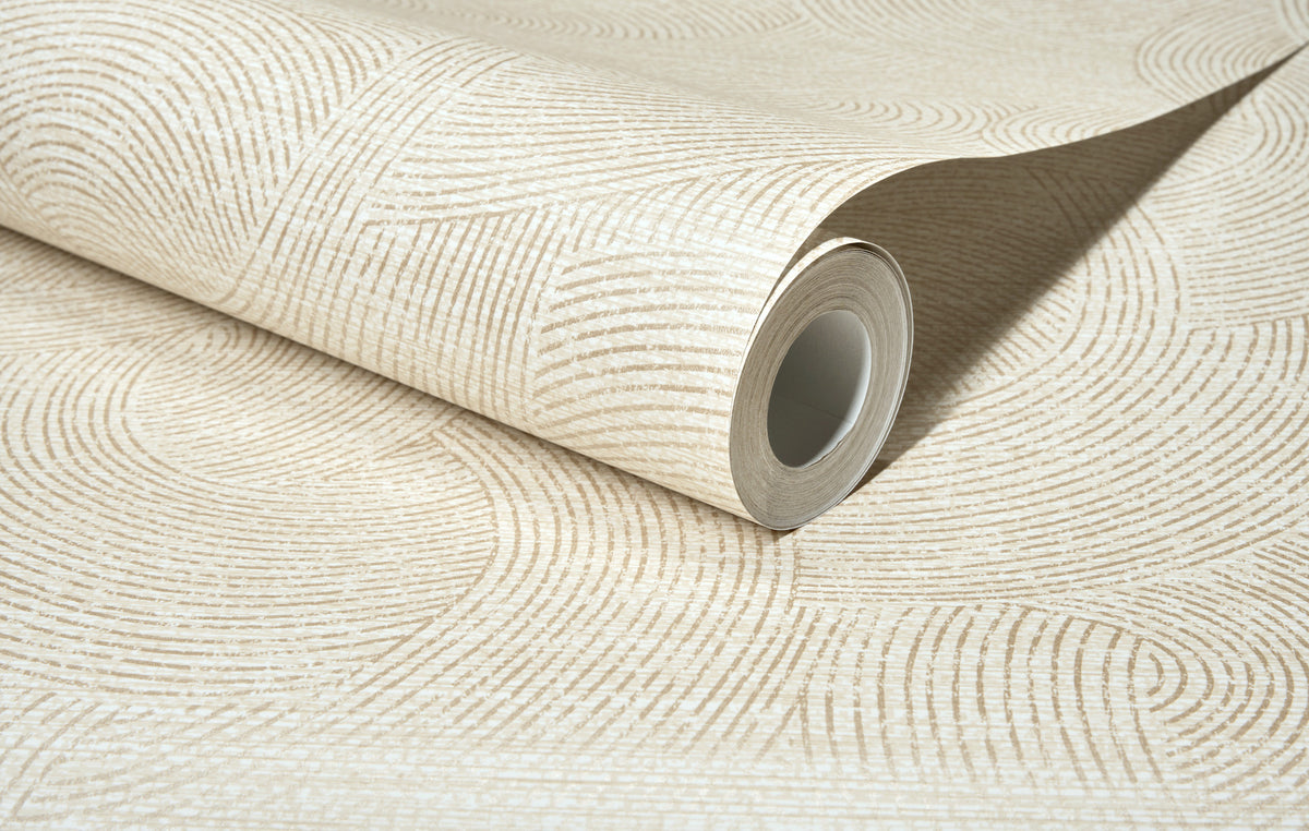 A close-up of the Chesapeake Harrison Swirling Geometric Wallpaper by York Wallcoverings, shown rolled up on a flat surface, featuring a subtle beige color with a textured pattern of concentric arcs and lines.