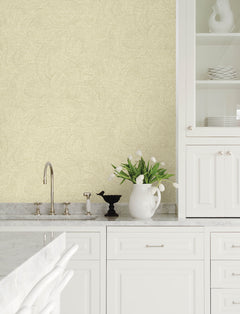Modern kitchen with white cabinets, marble countertops, a sink with a faucet, a vase of white tulips, a decorative black bird figure, and an open cabinet displaying white dishes set against walls adorned with Chesapeake Harrison Swirling Geometric Wallpaper by York Wallcoverings.