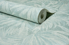A roll of Chesapeake Sonny Fronds Wallpaper by York Wallcoverings, featuring a light blue and white color palette with a subtle, textured botanical leaf pattern, is partially unrolled on a flat surface to reveal its elegant design.