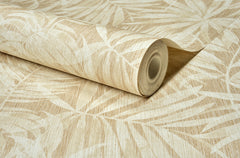 A roll of Chesapeake Sonny Fronds Wallpaper by York Wallcoverings, showcasing a beige and cream leafy pattern with tropical palm leaf designs, lies partially unrolled on a flat surface.