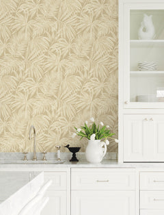 White kitchen with marble countertops, Chesapeake Sonny Fronds Wallpaper by York Wallcoverings in beige, glass-front cabinet, white ceramic pitcher with tulips, black bird decor, and chrome faucet.