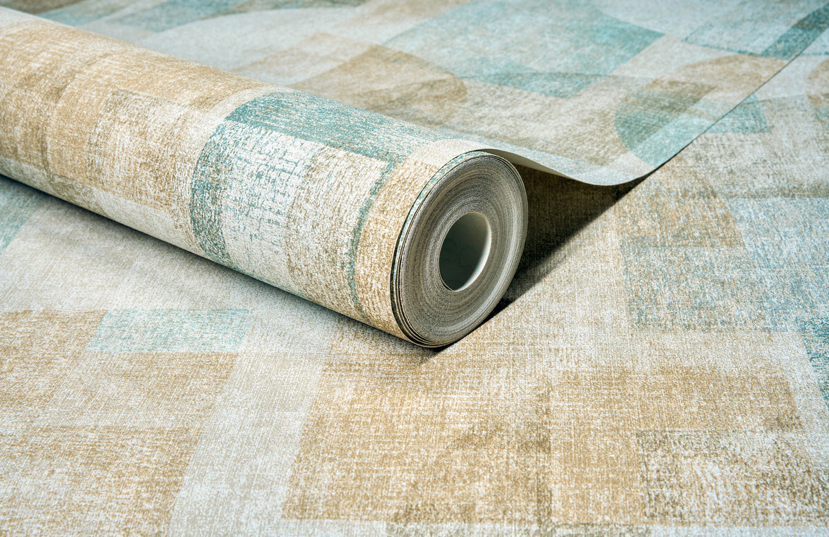 A close-up shows a partially unrolled roll of Chesapeake Cassandra Block Geometric Wallpaper by York Wallcoverings, featuring a textured beige and teal geometric pattern on a matching surface.