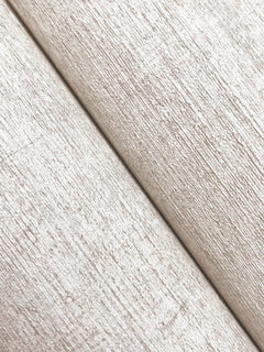 Close-up of two rolls of York Wallcoverings Chesapeake Tansy Distressed Wallpaper placed diagonally, displaying a subtle woodgrain-like pattern and soft sheen in textured beige.