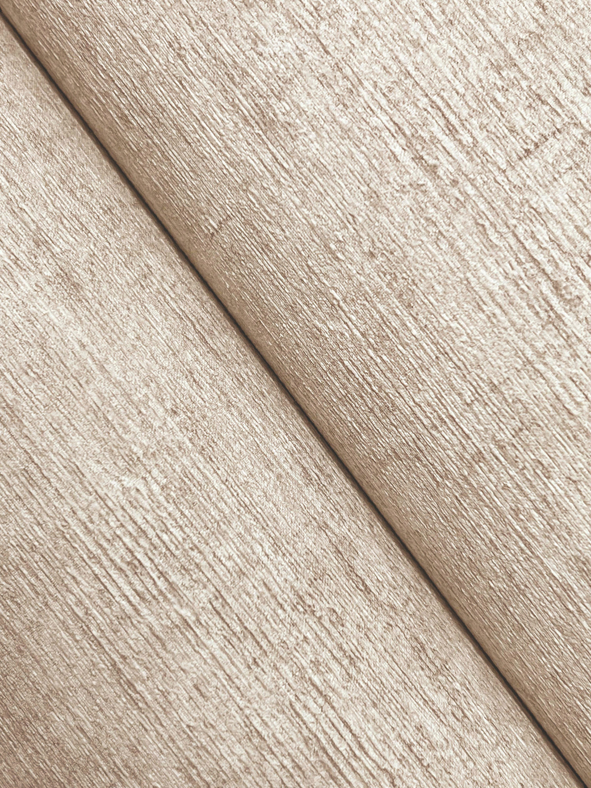 Close-up of two sheets of Chesapeake Tansy Distressed Wallpaper by York Wallcoverings in beige, showcasing a textured, fibrous surface and a visible diagonal seam at the center.