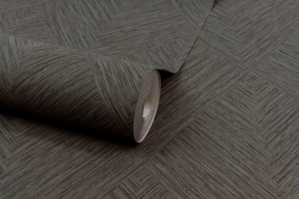 A partially unrolled roll of Chesapeake Hollis Textured Diamond Wallpaper by York Wallcoverings, featuring a subtle geometric diamond pattern in brown, is displayed on a matching surface.