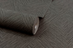 A partially unrolled roll of Chesapeake Hollis Textured Diamond Wallpaper by York Wallcoverings, featuring a subtle geometric diamond pattern in brown, is displayed on a matching surface.