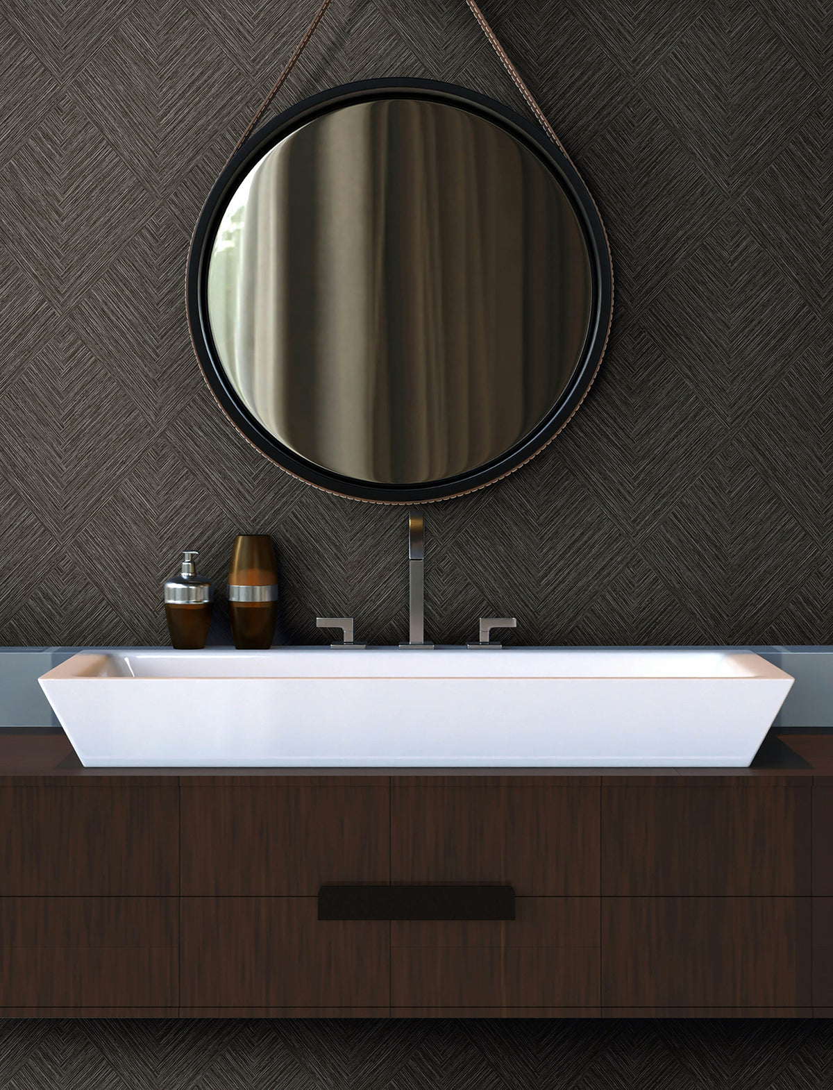 Modern bathroom with a round mirror, York Wallcoverings’ Chesapeake Hollis Textured Diamond Wallpaper on the walls, rectangular white sink, minimalist faucet, and two brown soap dispensers on a dark wooden vanity.