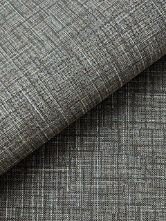 Close-up of Beau Faux Fabric Wallpaper by York Wallcoverings, showcasing a textured gray surface with a woven, crisscross pattern. One section is folded over, revealing a subtle variation in shading and texture.
