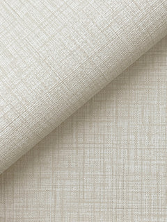 A close-up of York Wallcoverings’ Beau Faux Fabric Wallpaper in light beige, featuring a subtle crisscross pattern and a linen-like texture with fine intersecting lines, partially rolled on a matching flat surface.