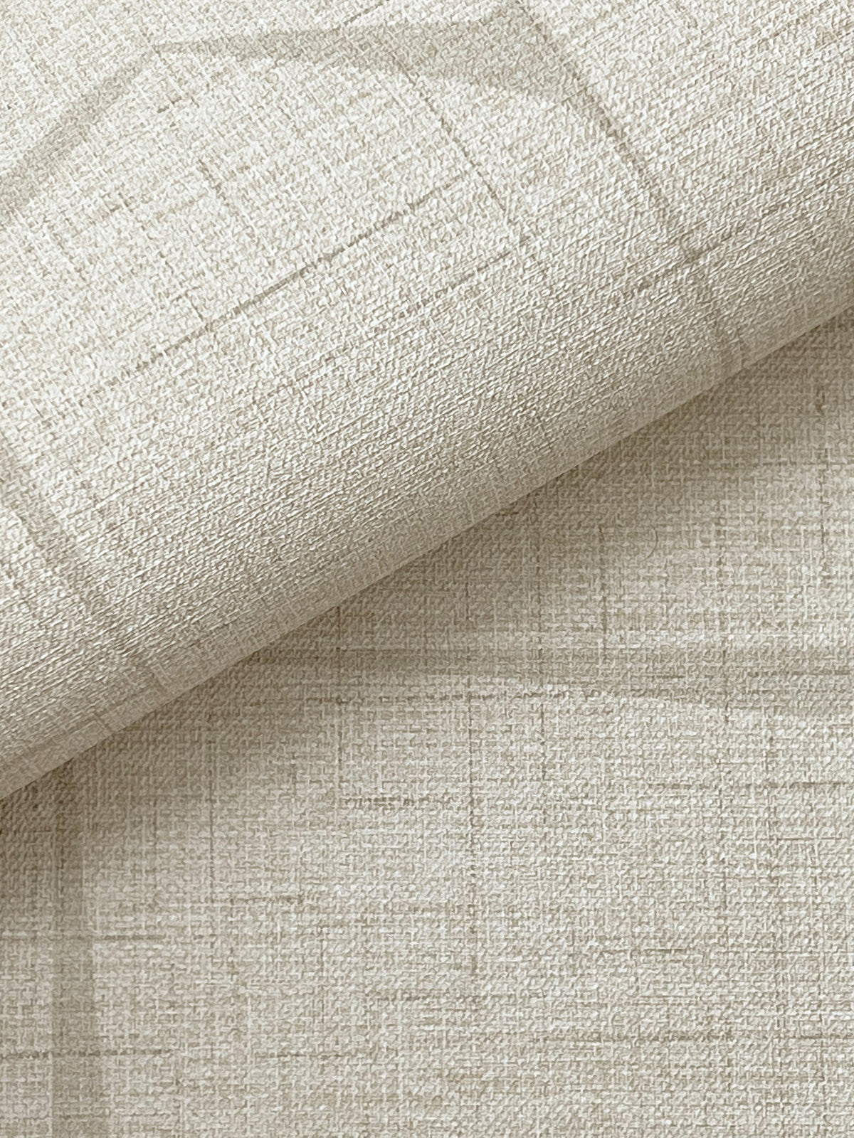 A close-up view of the Lyle Abstract Geometric Wallpaper by York Wallcoverings reveals its textured, beige surface with a subtle grid pattern and slight folds at the top, showcasing the intricate weave and neutral color.