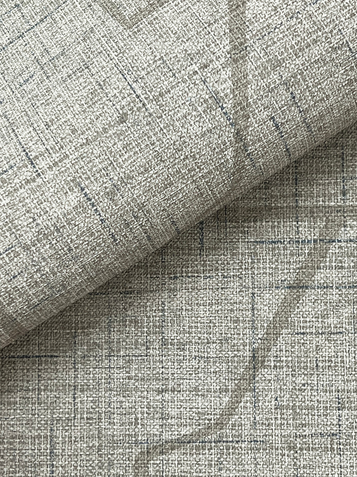 Close-up of the Lyle Abstract Geometric Wallpaper by York Wallcoverings in light gray, featuring a subtle grid pattern and visible weave with thin intersecting lines. A folded section highlights the minimalist, modern aesthetic of the design.