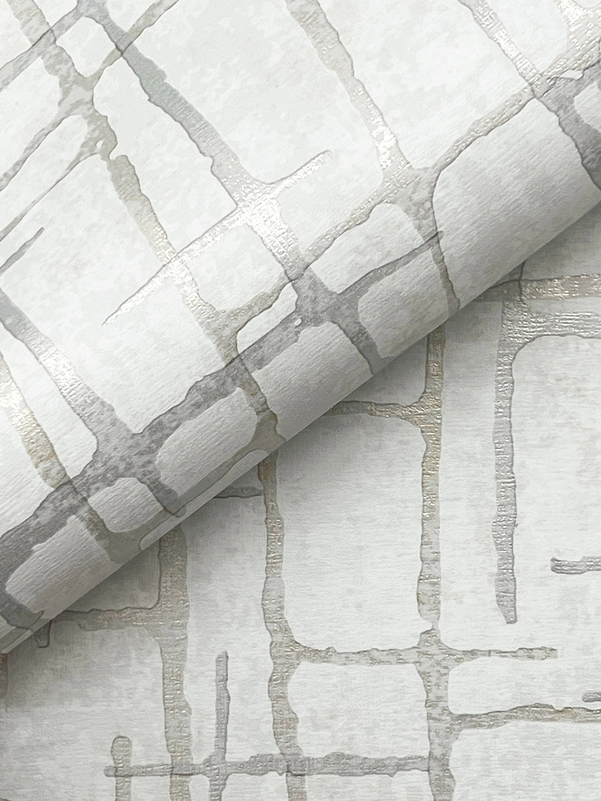 Introducing the Rian Linear Abstract Wallpaper by York Wallcoverings, featuring a rolled wallpaper design with a metallic silver and beige geometric pattern of intersecting lines on a subtly textured light background for a modern, abstract look.