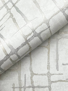 Introducing the Rian Linear Abstract Wallpaper by York Wallcoverings, featuring a rolled wallpaper design with a metallic silver and beige geometric pattern of intersecting lines on a subtly textured light background for a modern, abstract look.