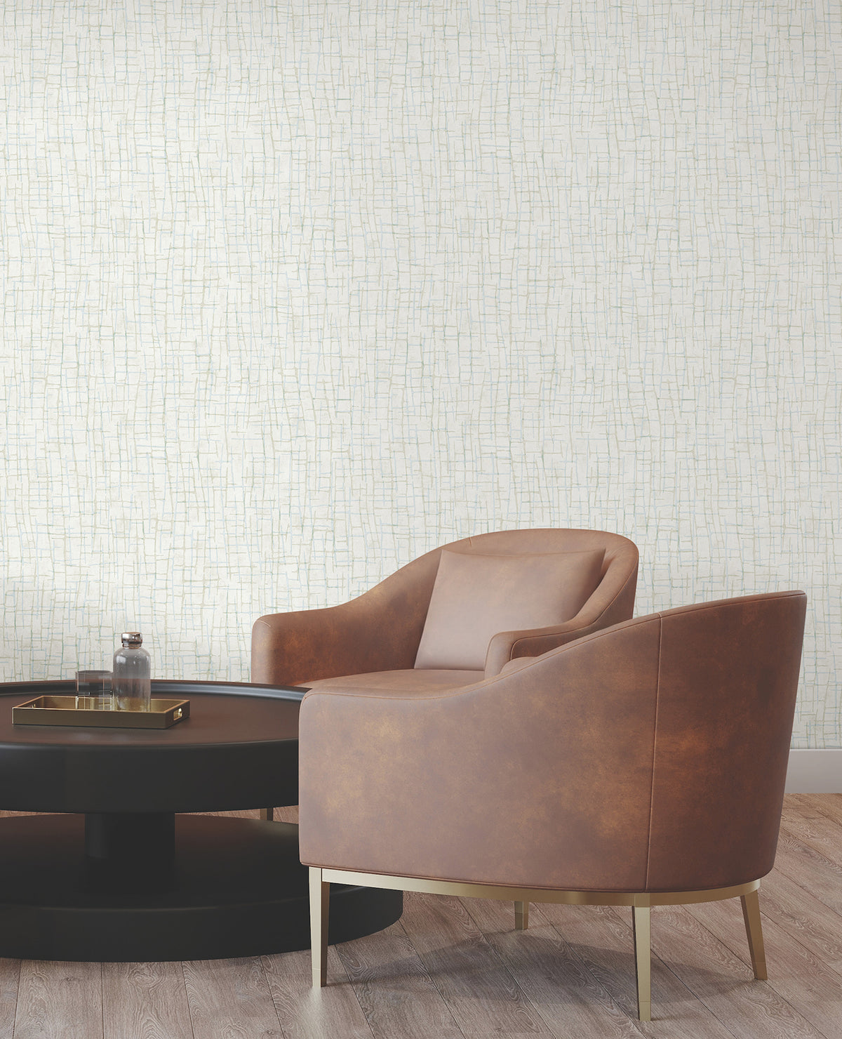 Two brown armchairs with gold legs sit by a round black coffee table topped with a glass bottle and tray, set against York Wallcoverings’ Rian Linear Abstract Wallpaper and a wooden floor.