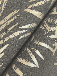 Close-up of Allerton Bamboo Wallpaper featuring a metallic gold abstract leaf pattern on a dark background. The wallpaper is shown with a diagonal fold through the center of the image, highlighting its textured surface.