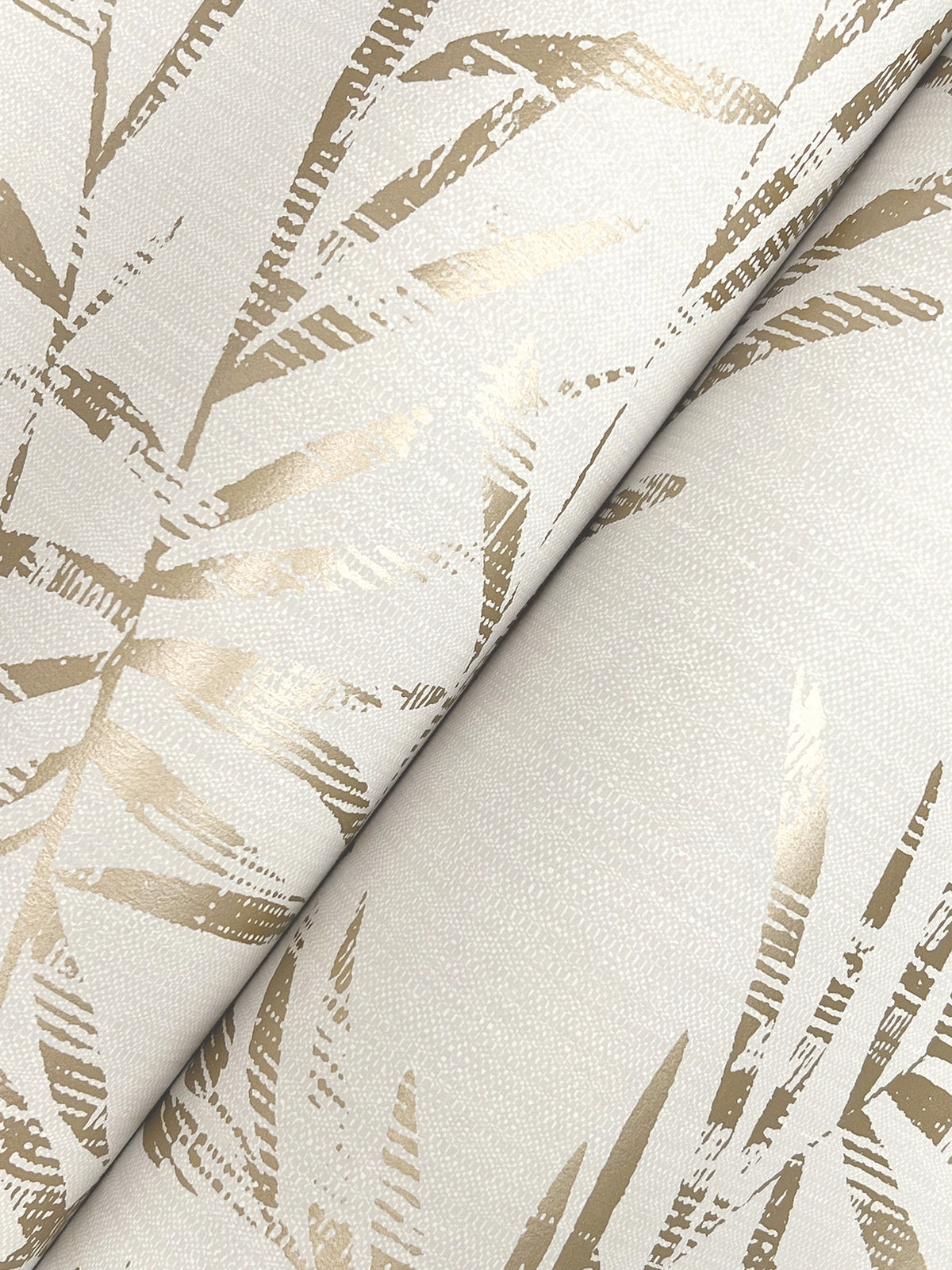 A close-up of Allerton Bamboo Wallpaper, showcasing a beige design with overlapping abstract gold metallic leaves on a textured, light background.