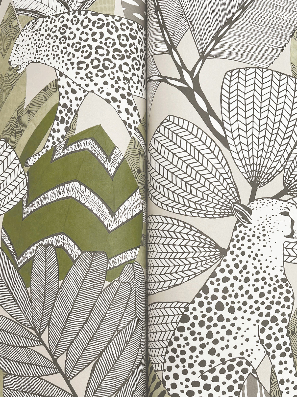 Experience the Namiri Wallpaper by York Wallcoverings, featuring two stylized leopards with black spots strolling amidst large, patterned leaves in a black, white, and muted green palette. The hand-drawn, decorative jungle scene is elegantly divided by the wallpaper’s fold.