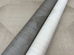 Two rolls of In Clay Wallpaper featuring a subtle geometric pattern in charcoal and off-white.