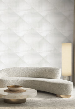 In Clay Wallpaper by York Wallcoverings in a light gray repeating diamond pattern on a wall behind a curved sofa, a marble coffee table, and a tall floor lamp.
