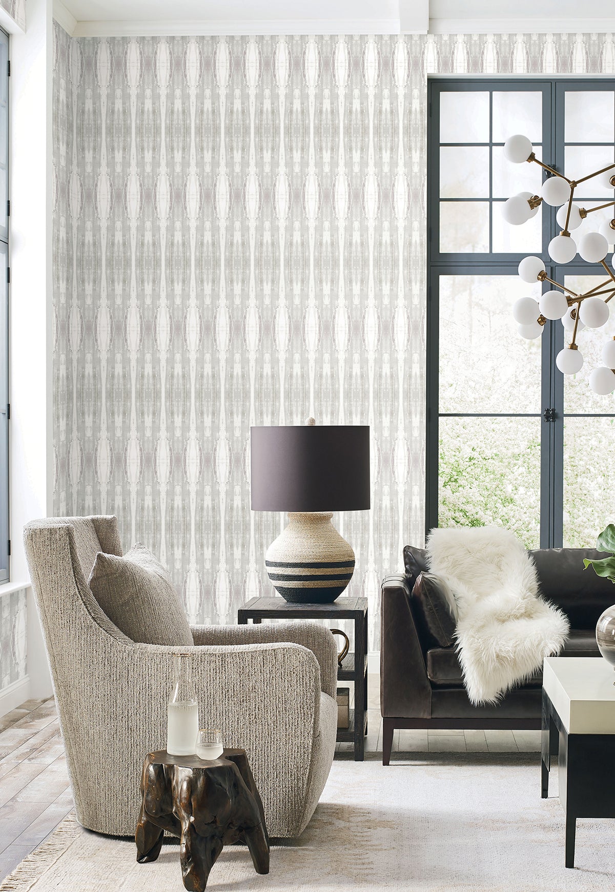 Escalante Wallpaper by York Wallcoverings featuring a vertical, abstract striped pattern in shades of gray and white on a living room wall.