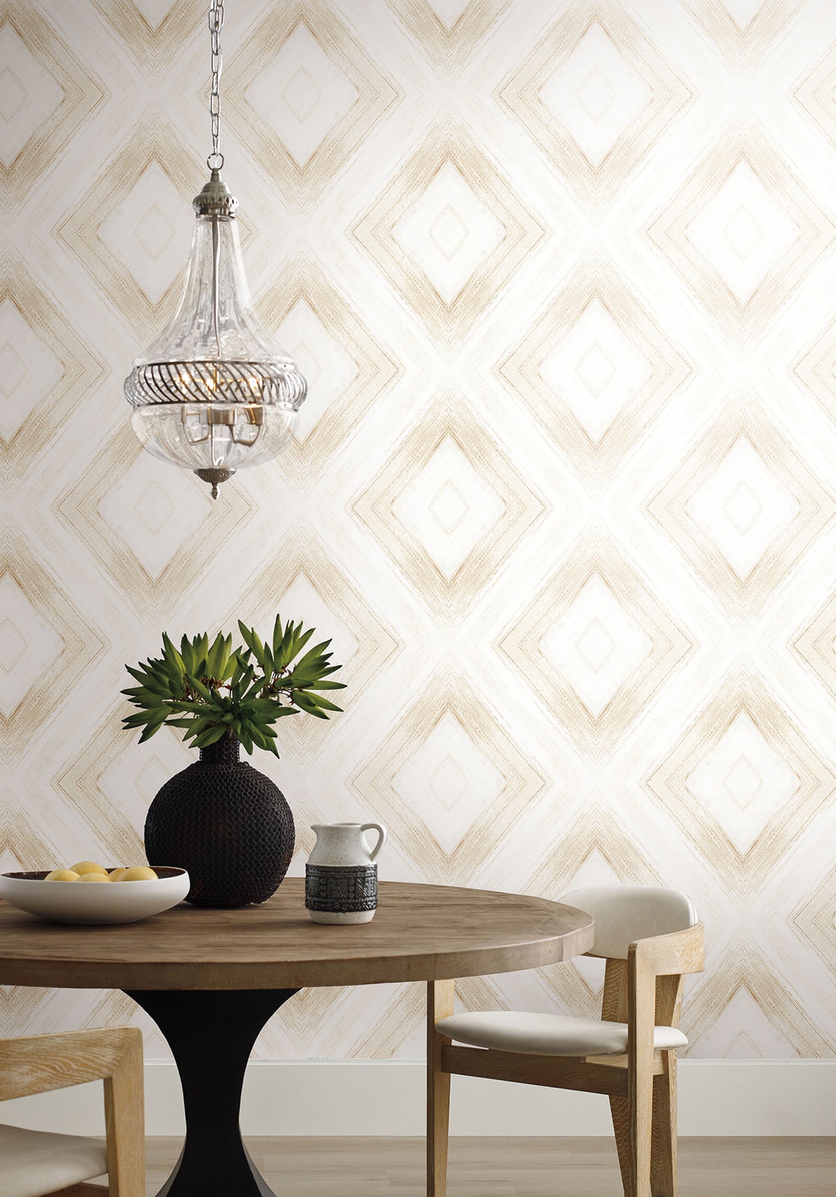 Ballad Wallpaper featuring a white background with a large, light brown diamond pattern, shown in a dining area with a round wooden table, chairs, a glass pendant light, and a vase.