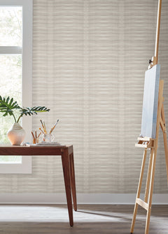Grey Stone Wallpaper with a subtle light grey horizontal ribbed pattern covering a wall in a room featuring a wooden table, a plant, and an artist’s easel.