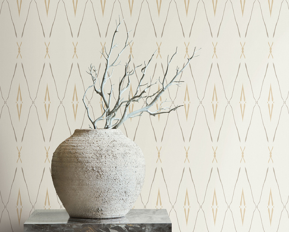 A textured stone vase holding bare branches sits in front of Artifact Silhouettes Wallpaper featuring a repeating geometric diamond pattern.