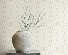 A textured stone vase holding bare branches sits in front of Artifact Silhouettes Wallpaper featuring a repeating geometric diamond pattern.