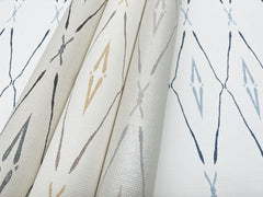 Three rolls and one flat sheet of York Wallcoverings Artifact Silhouettes wallpaper, featuring a repeating diamond and cross pattern in gray, tan, and blue.