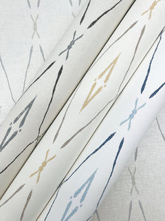 Three rolls of York Wallcoverings Artifact Silhouettes wallpaper featuring a repeating pattern of elongated, diamond-shaped geometric motifs in blue, tan, and gray on a textured off-white background.