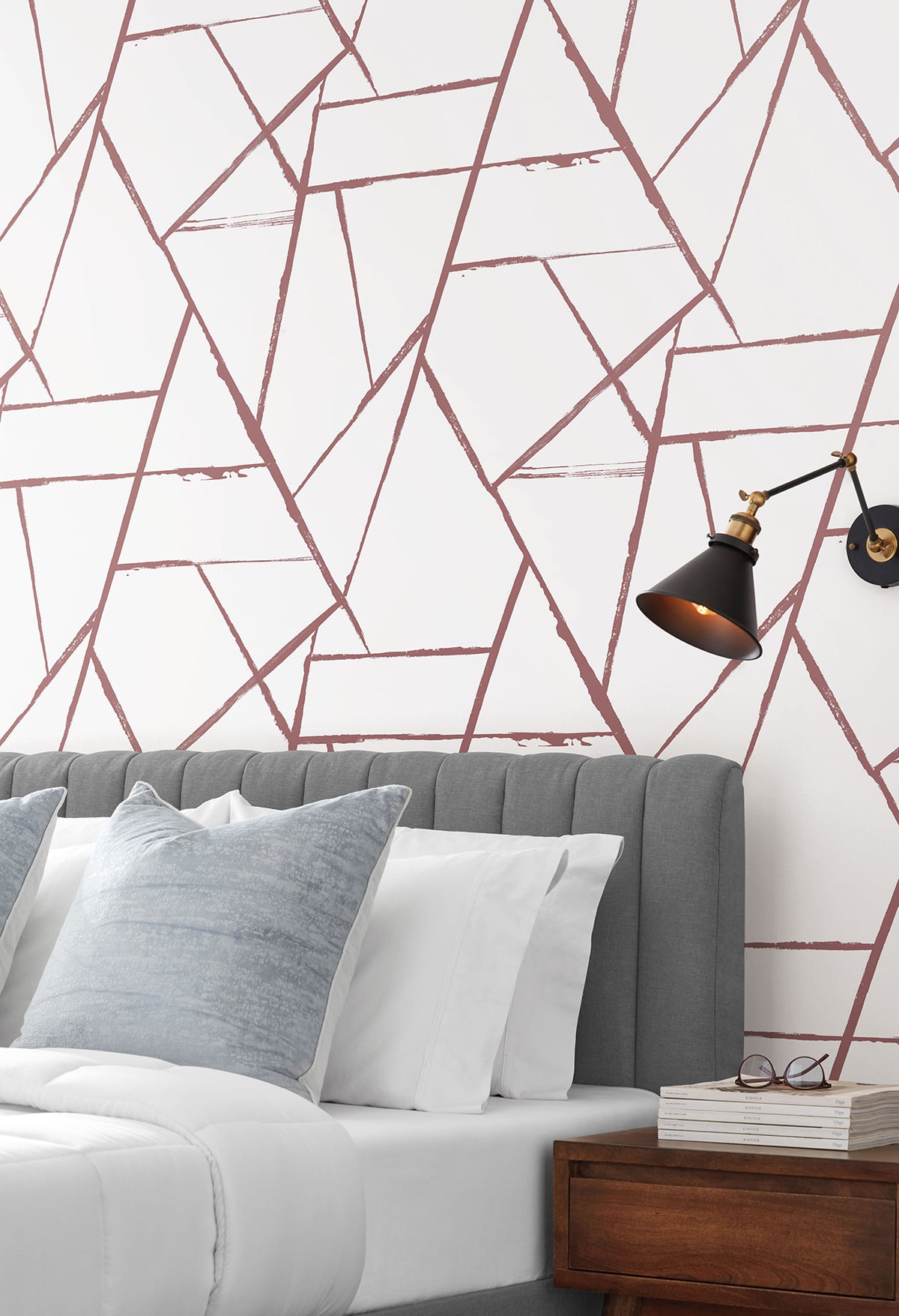 Intersect Wallpaper featuring a geometric pattern of intersecting, distressed mauve lines on a white background, installed behind a gray tufted headboard.