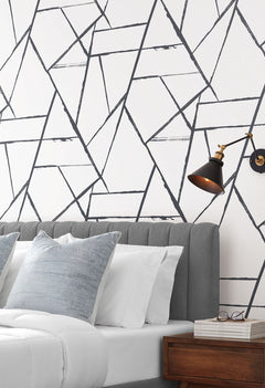 Intersect Wallpaper featuring a geometric pattern of overlapping black lines on a white background installed behind a bed.