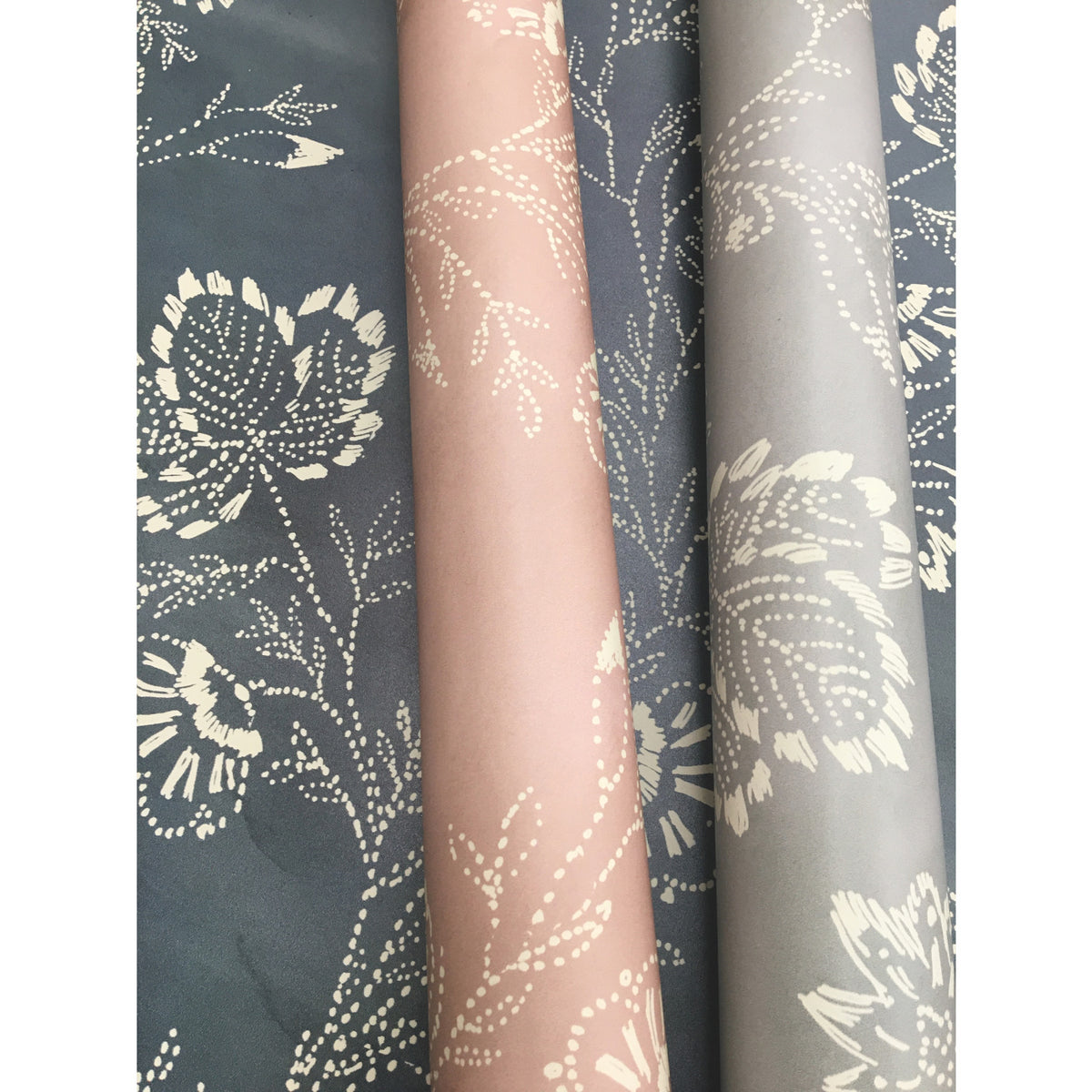 Three rolls of Barbier Wallpaper featuring a dotted floral pattern in pink, light gray, and dark gray.